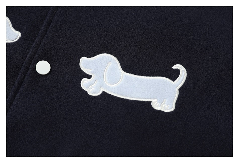 Close-up of a pale blue embroidered dog appliqué and white snap button on navy jacket fabric.