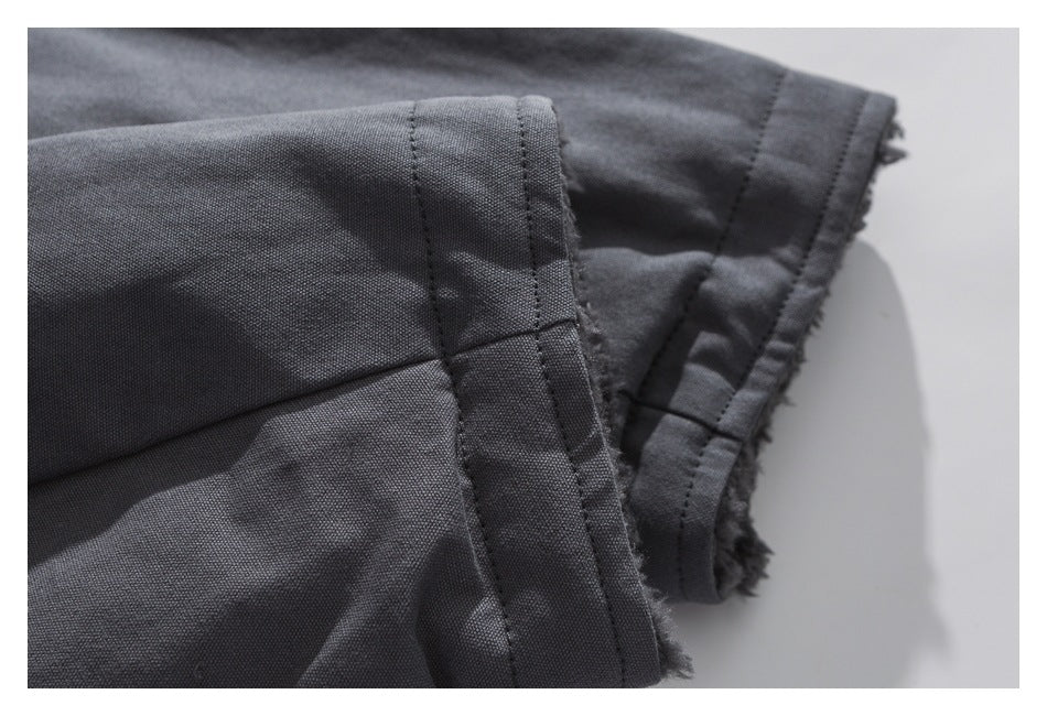 Close-up of dark gray fabric showing stitched seams and a frayed raw edge.