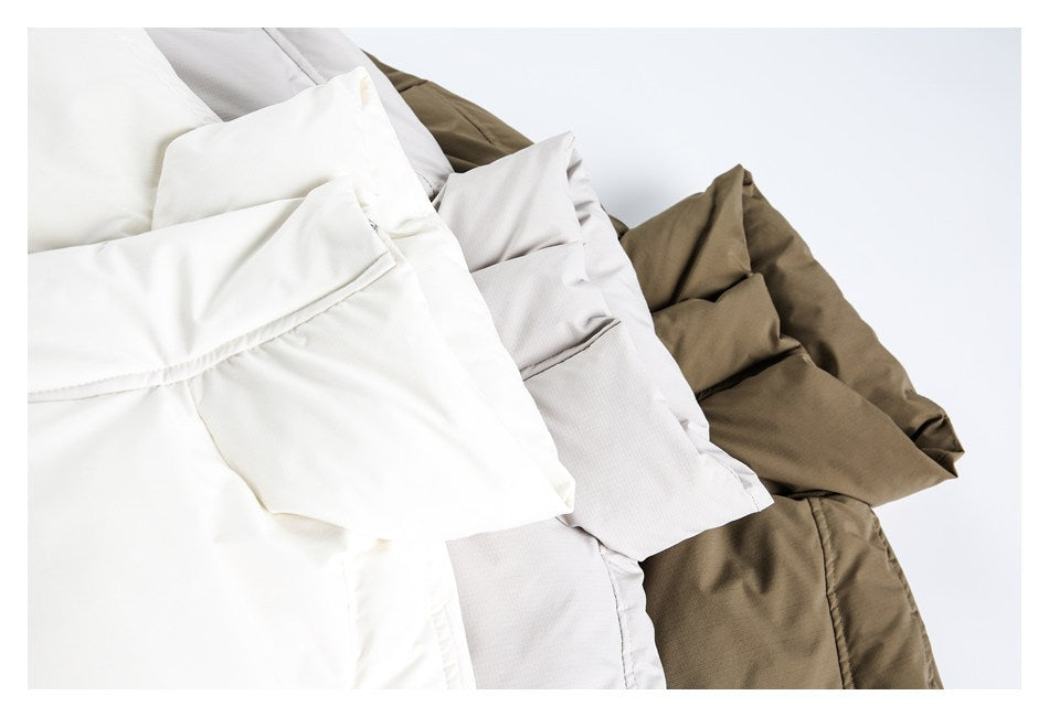 Three folded garments in ivory, light gray, and olive, arranged to show their collars and fabric.