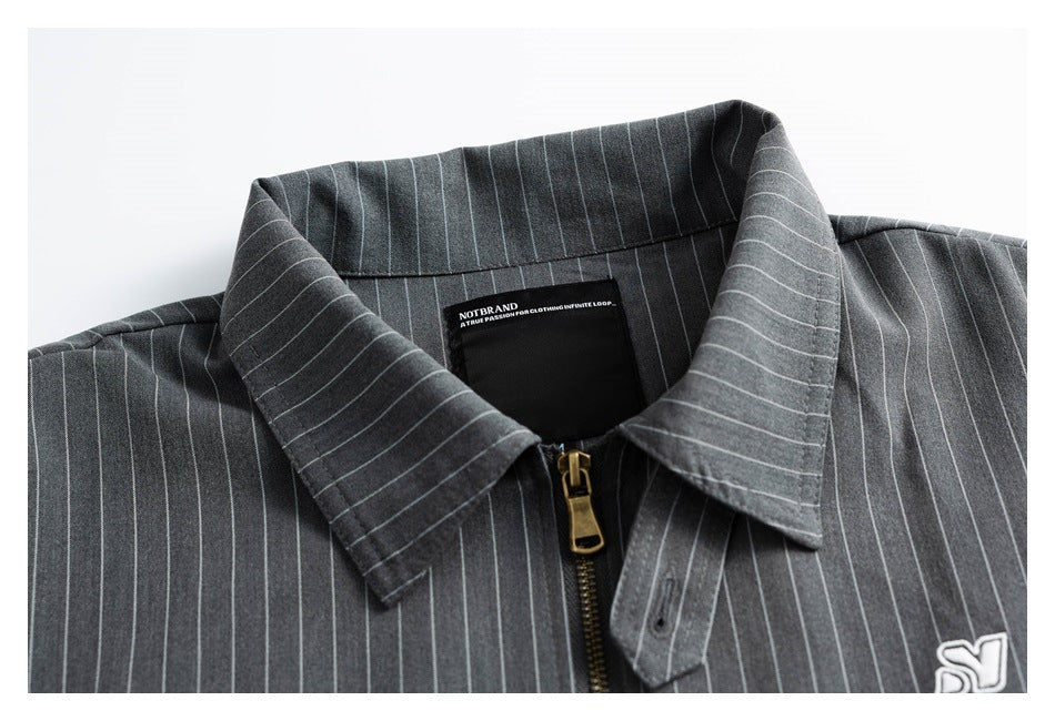 Charcoal pinstripe shirt collar and brass zipper, with an inner neck label and partial chest emblem.