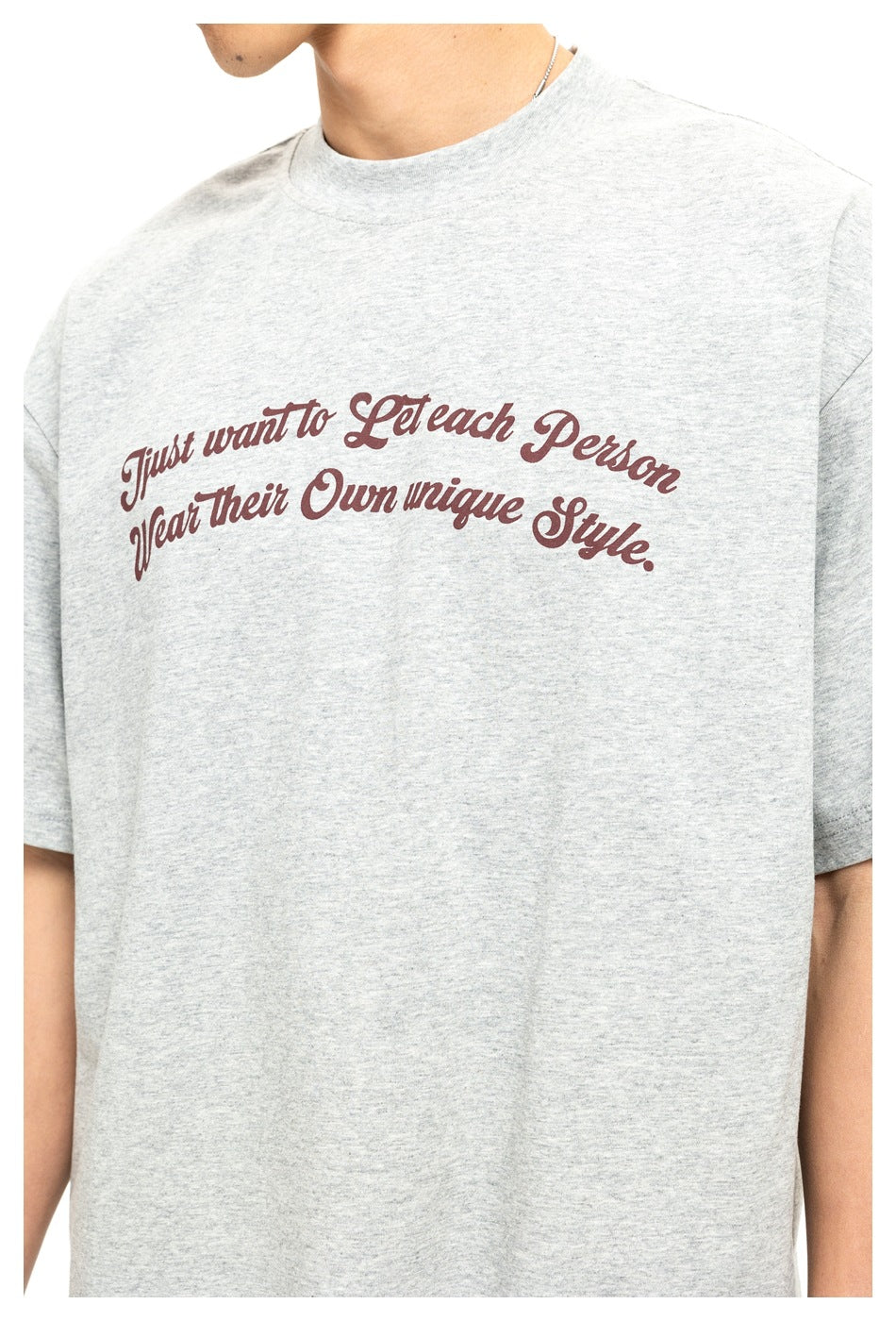 Close-up of a light gray T-shirt with burgundy script reading “Just want to Let each Person Wear their Own unique Style.”