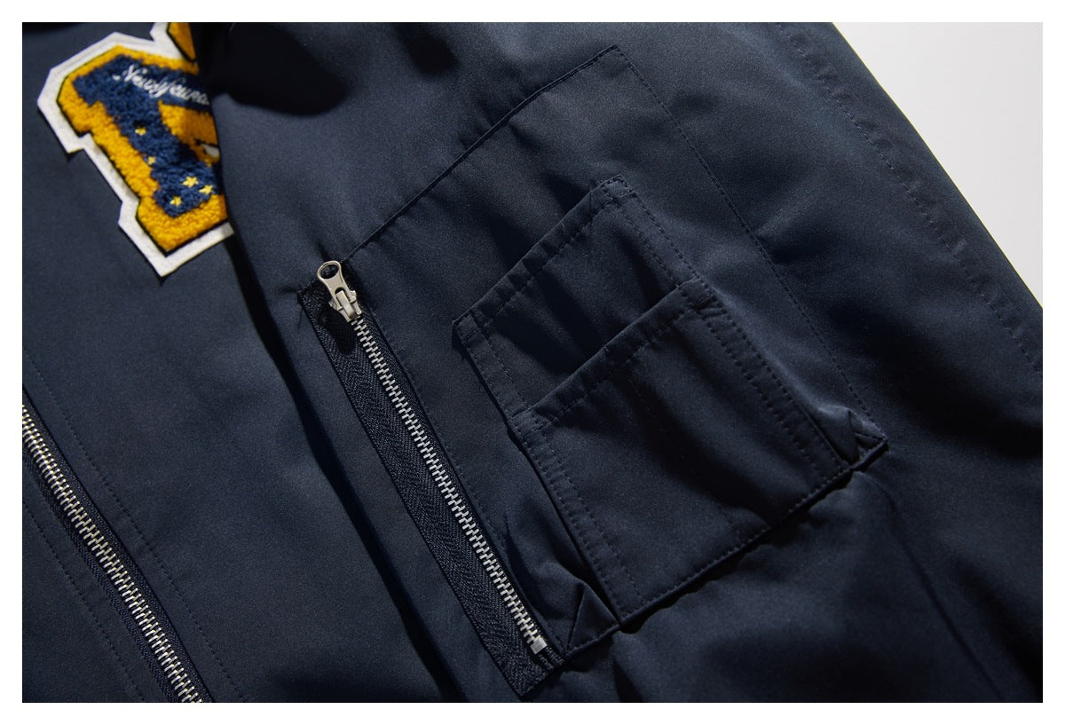 Close-up of a dark navy jacket showing an embroidered patch and a small zippered pocket.