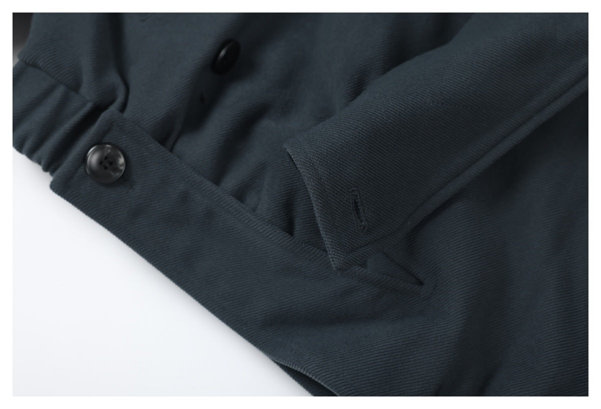 Close-up of a dark charcoal garment showing overlapping fabric panels and two black buttons.