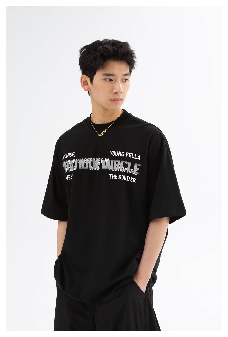 Model wearing a black oversized T-shirt with layered white chest lettering, shown from the front.