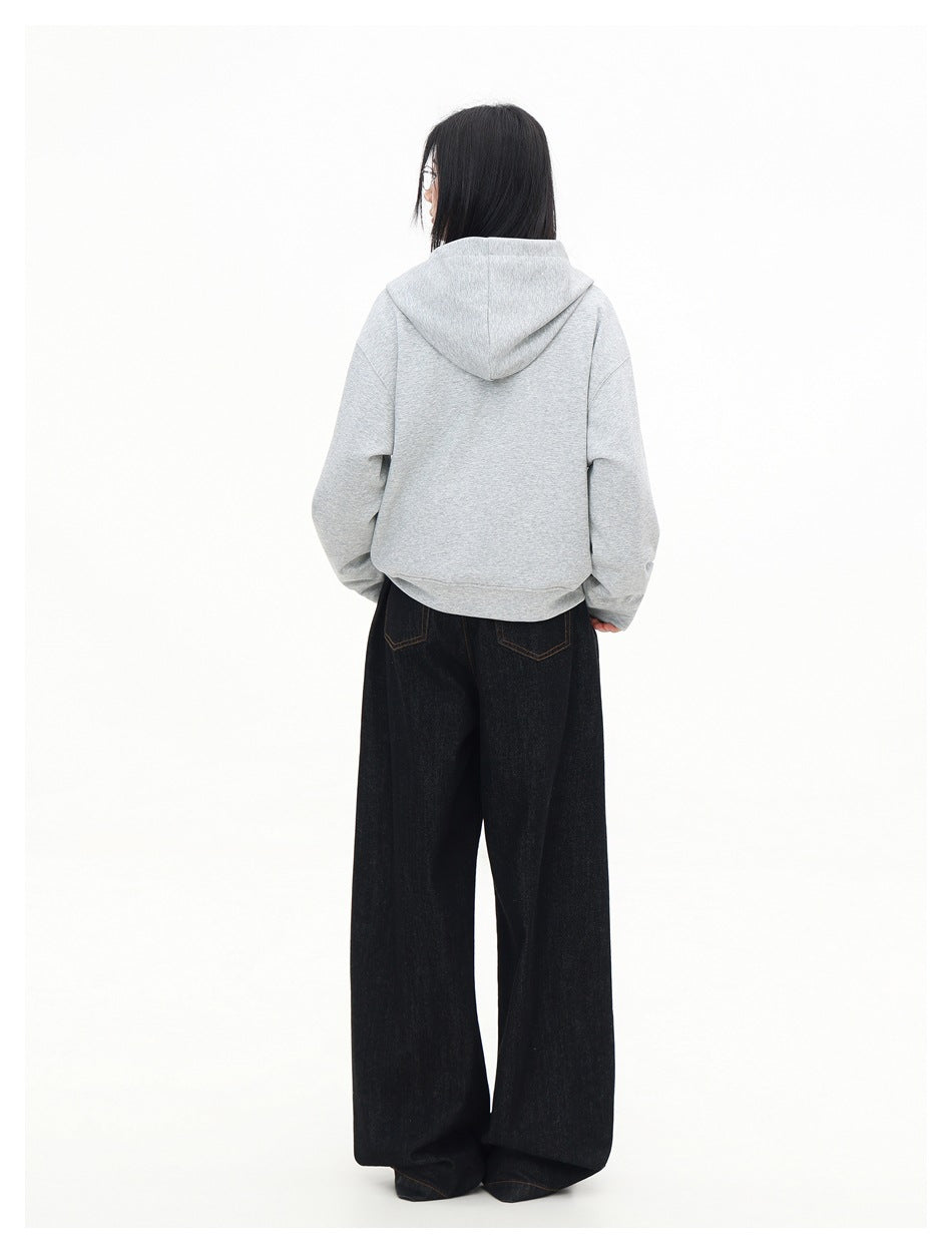 Rear view of a model wearing the light gray hooded sweatshirt with wide black jeans.