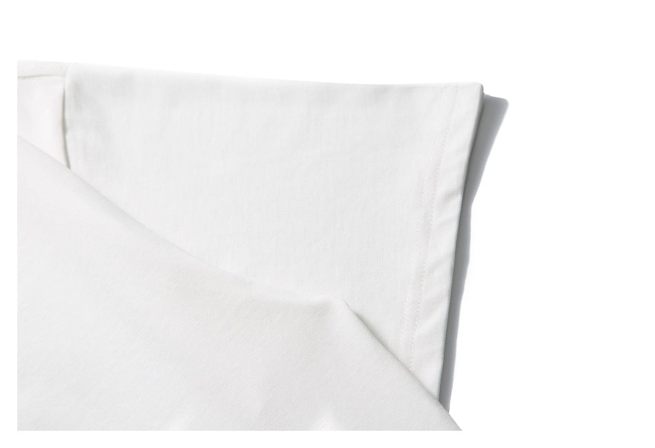 Close-up of a white garment folded to show a stitched edge and seam.