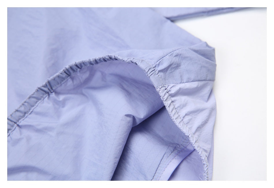 Close-up of lavender fabric with curved gathered stitching and a stitched seam.