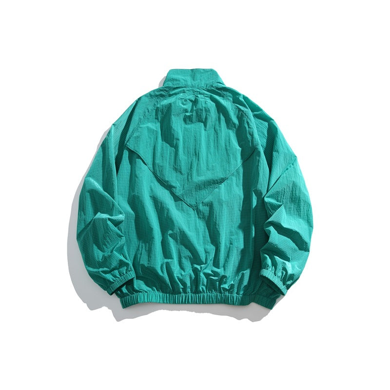 Turquoise jacket shown from the back, with a layered flap, high collar, elastic cuffs and hem.