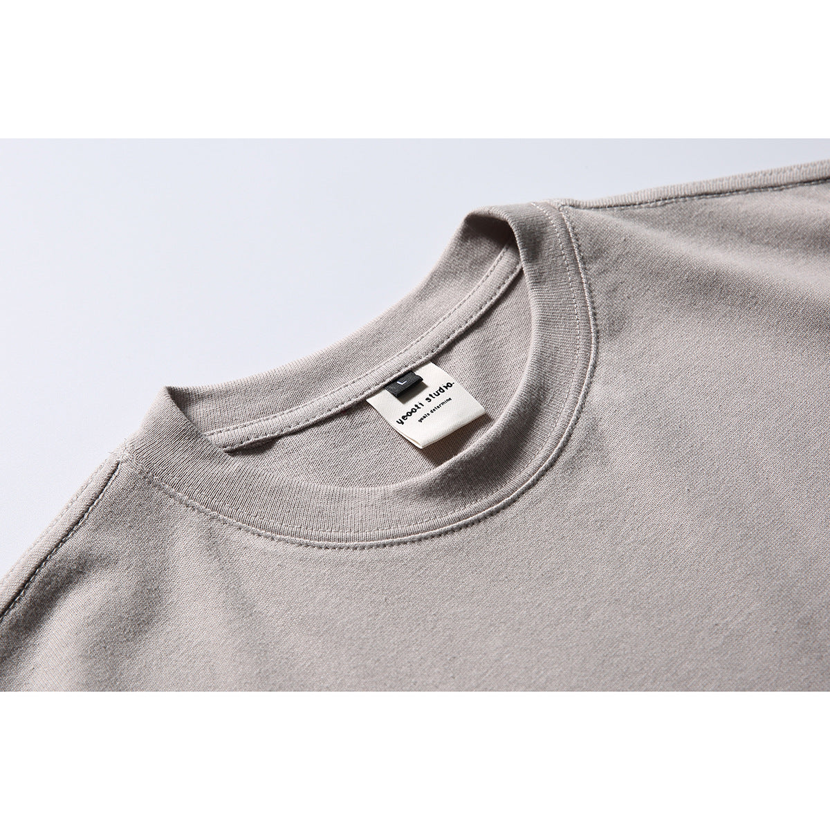 Close-up of a light taupe T-shirt's ribbed crew neck and sewn-in neck label.