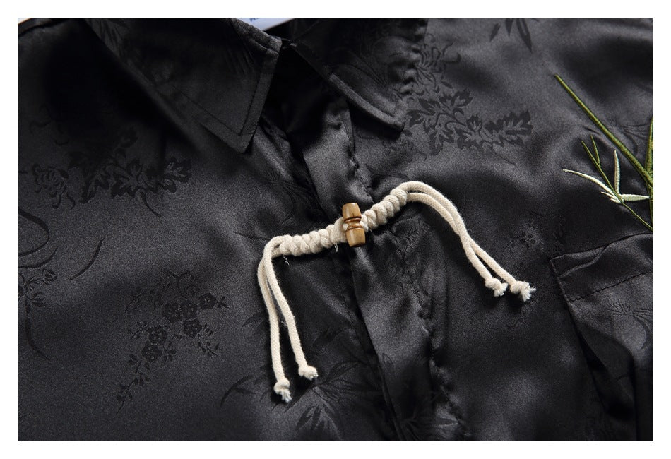 Close-up of a black floral-patterned shirt showing cream rope frog closures with wooden toggles.