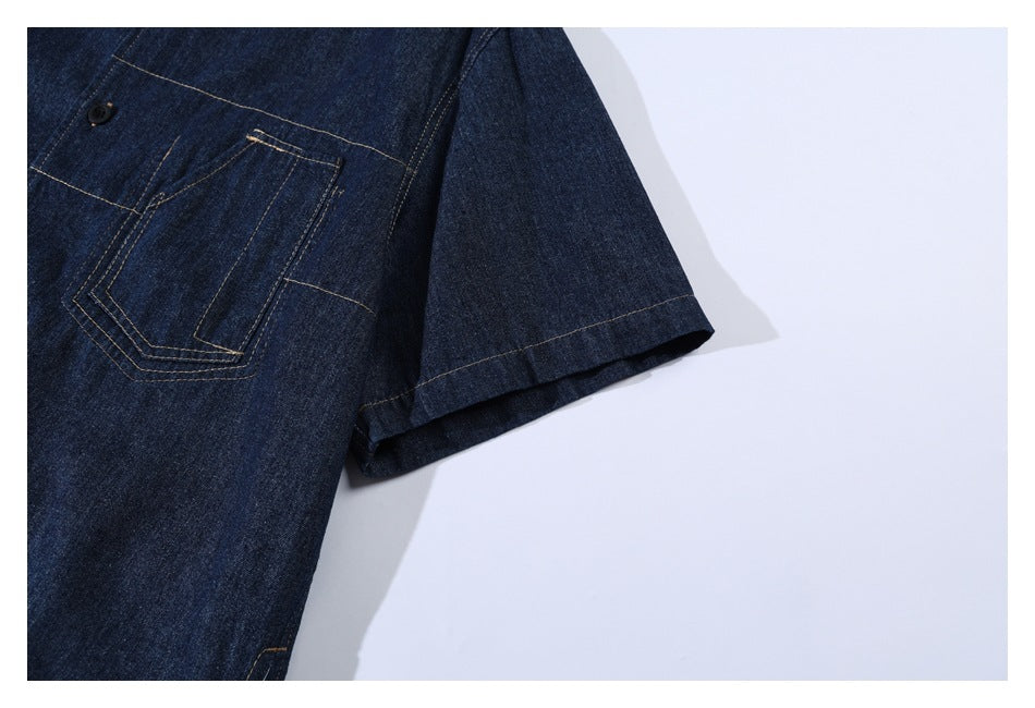 Dark indigo denim short sleeve and chest pocket with angular tan topstitching and a black button.
