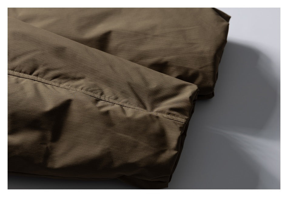 Close-up of a stitched seam and folded edge on olive-brown garment fabric.