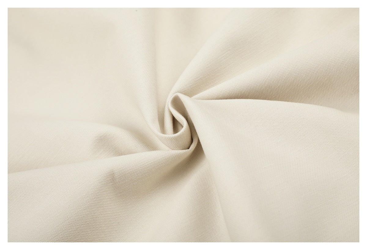 Close-up of ivory fabric draped into soft folds, showing its fine woven texture.