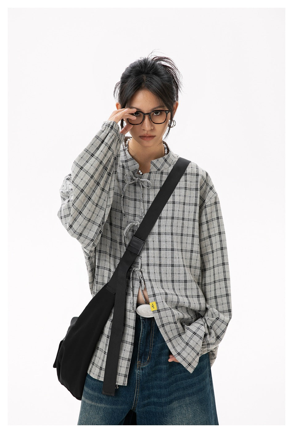 Closer front view of a model wearing a gray plaid blouse with loop closures and voluminous sleeves.