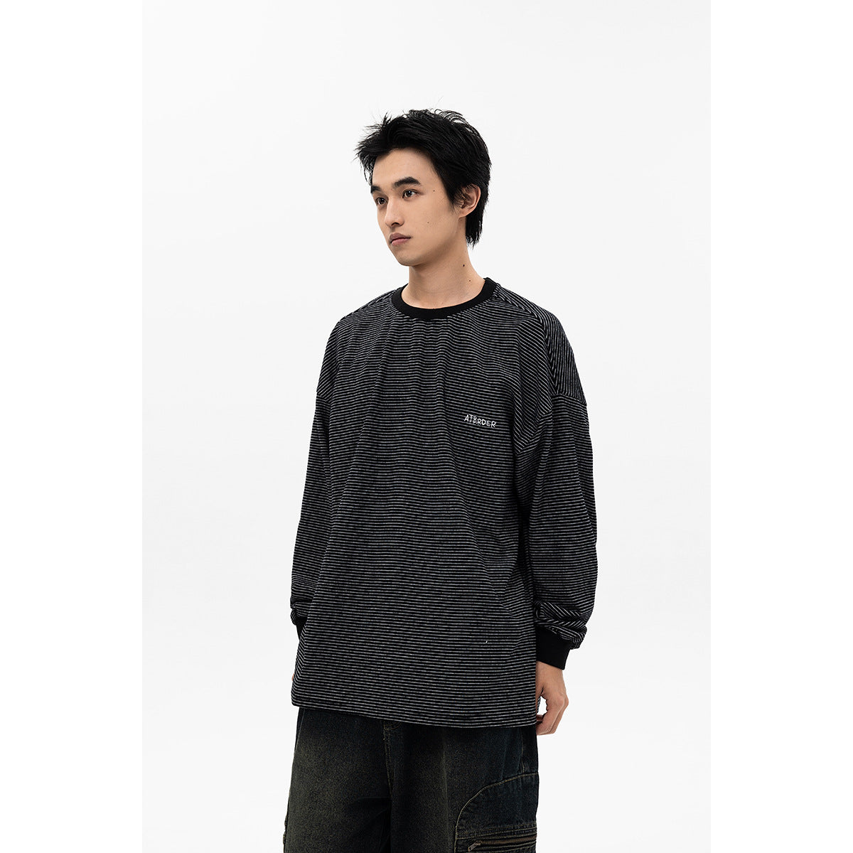 Man modeling a loose black long-sleeve shirt with fine gray stripes, black ribbed trim, and small chest lettering.