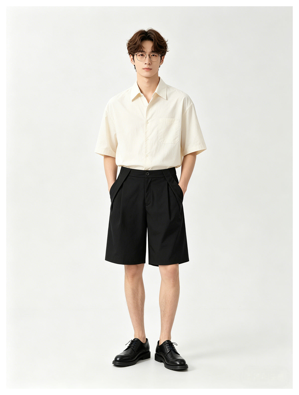 Model wearing a cream short-sleeve button-up shirt with a chest pocket and black pleated shorts.