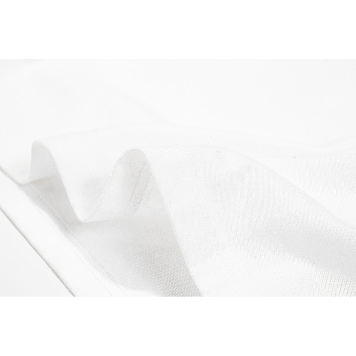 Close-up of white T-shirt fabric folded to show its stitched edge and texture.
