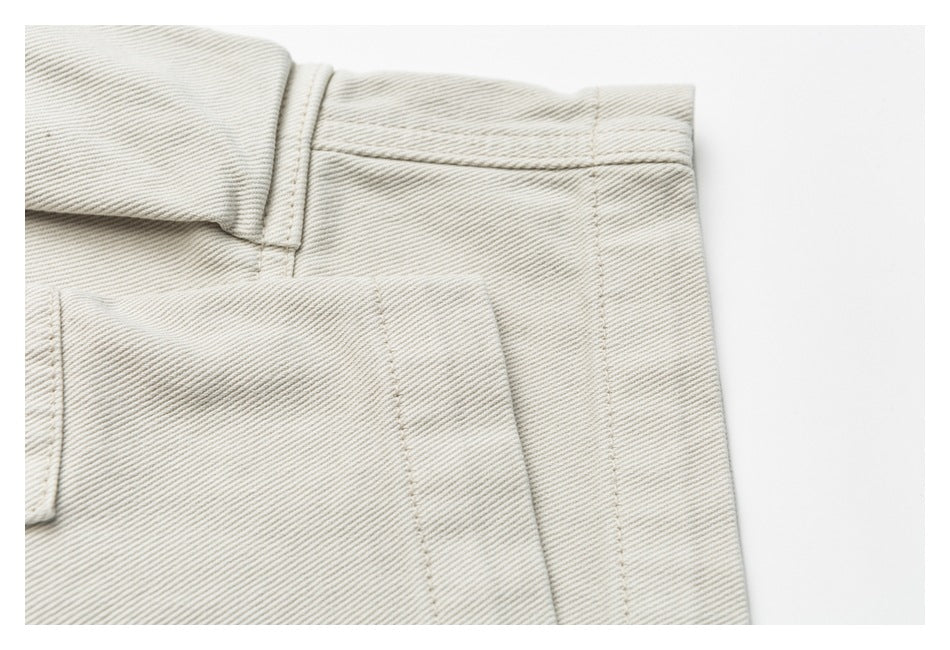 Close-up of off-white trousers showing the waistband, belt loop, and rear pocket seam.