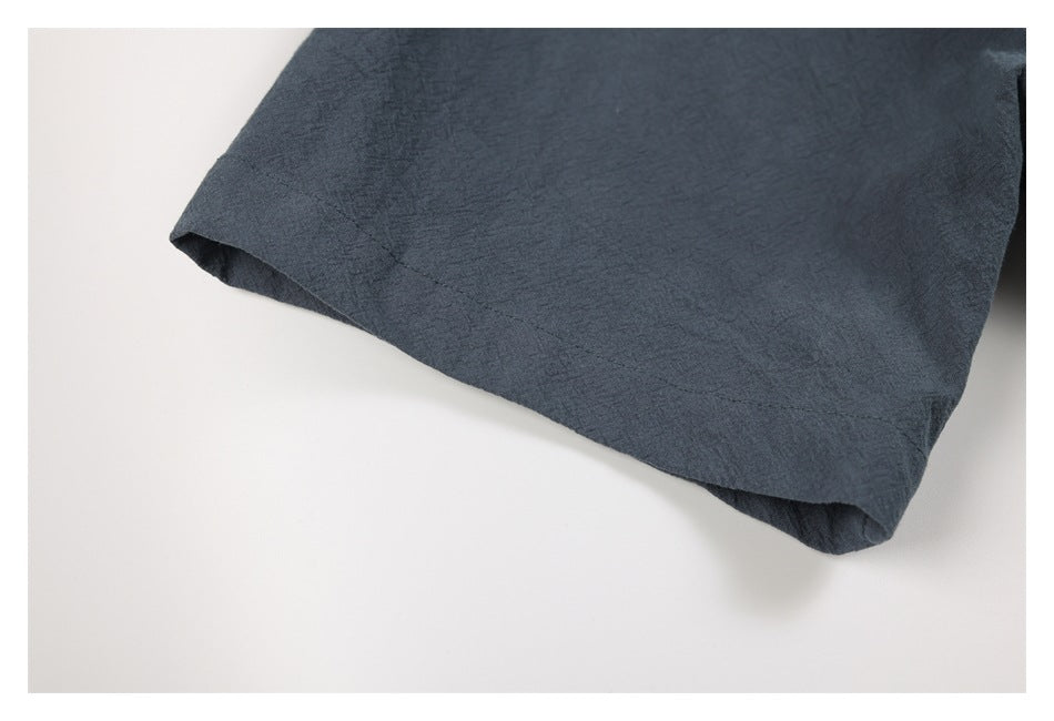 Close-up of a charcoal-blue garment edge with a stitched seam and folded hem.