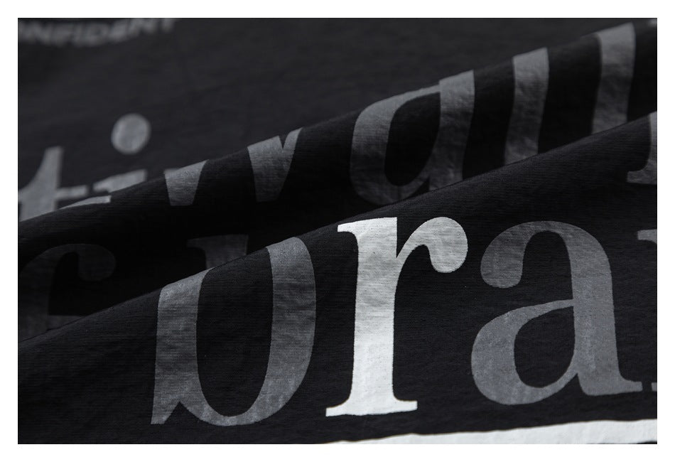 Close-up of oversized gray and white printed lettering across folded black fabric.