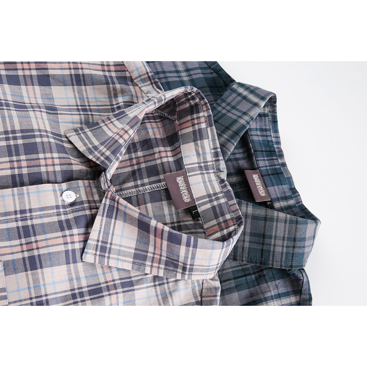 Close-up of two plaid short-sleeve shirts showing their collars, inner labels, and button placket.