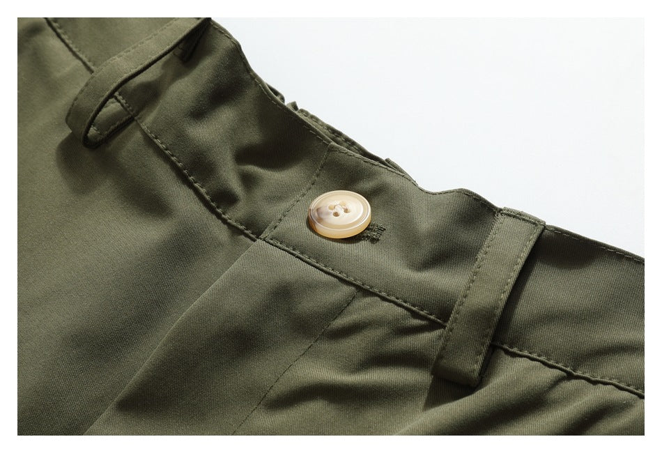Close-up of olive-green trousers showing the waistband, belt loops, and cream button.