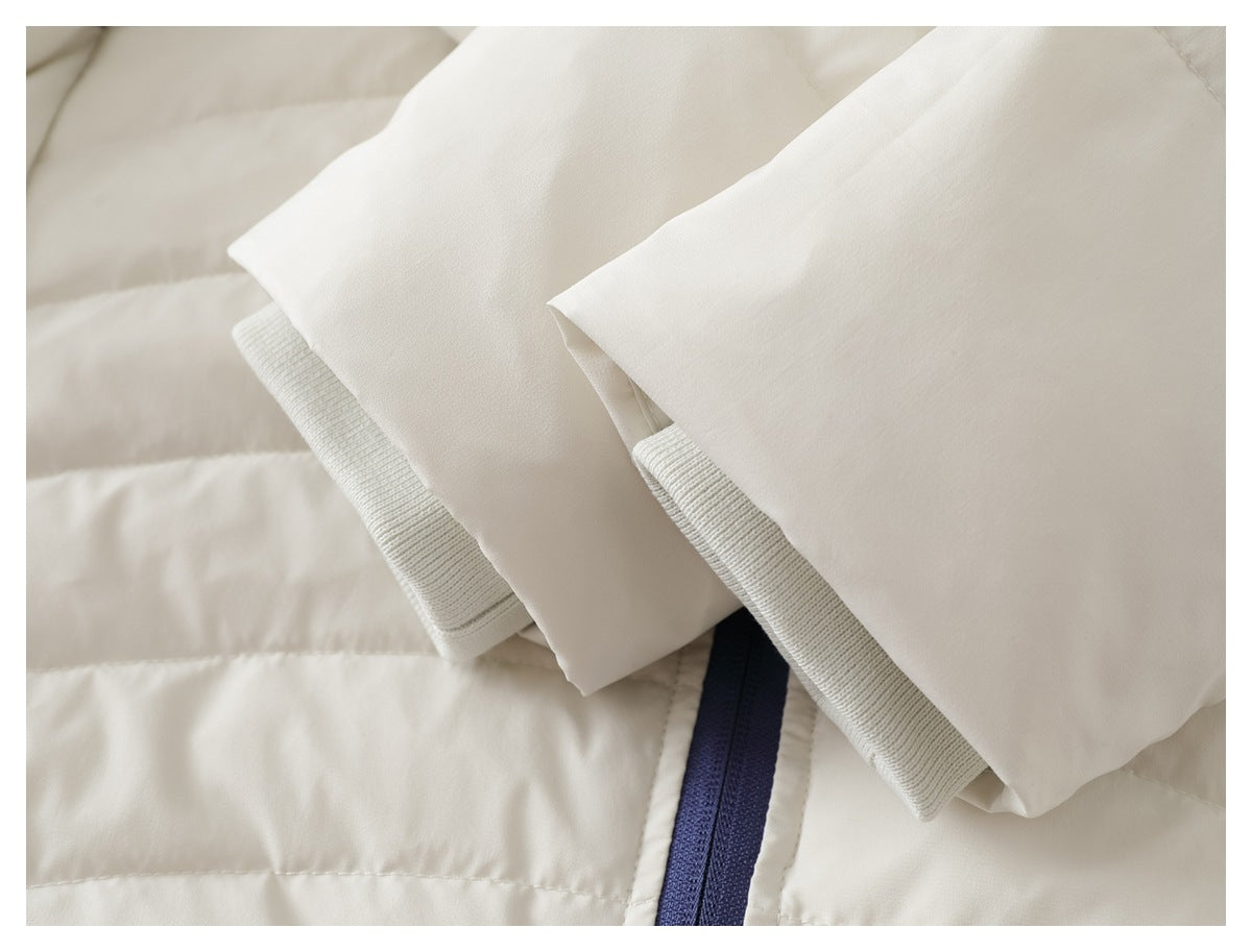 Close-up of white jacket sleeves with ribbed knit cuffs over quilted fabric and a blue zipper.