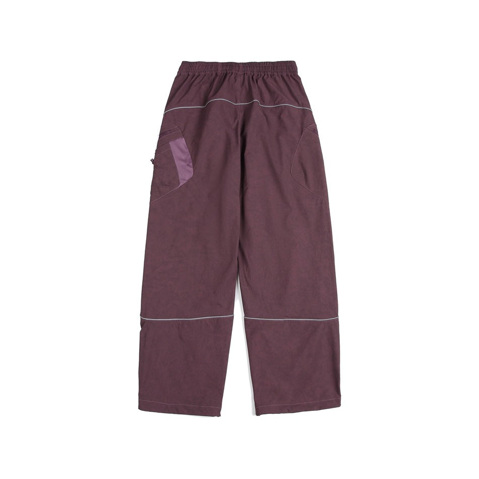 Back view of loose plum cargo pants with curved pockets and light piping across the seat and lower legs.