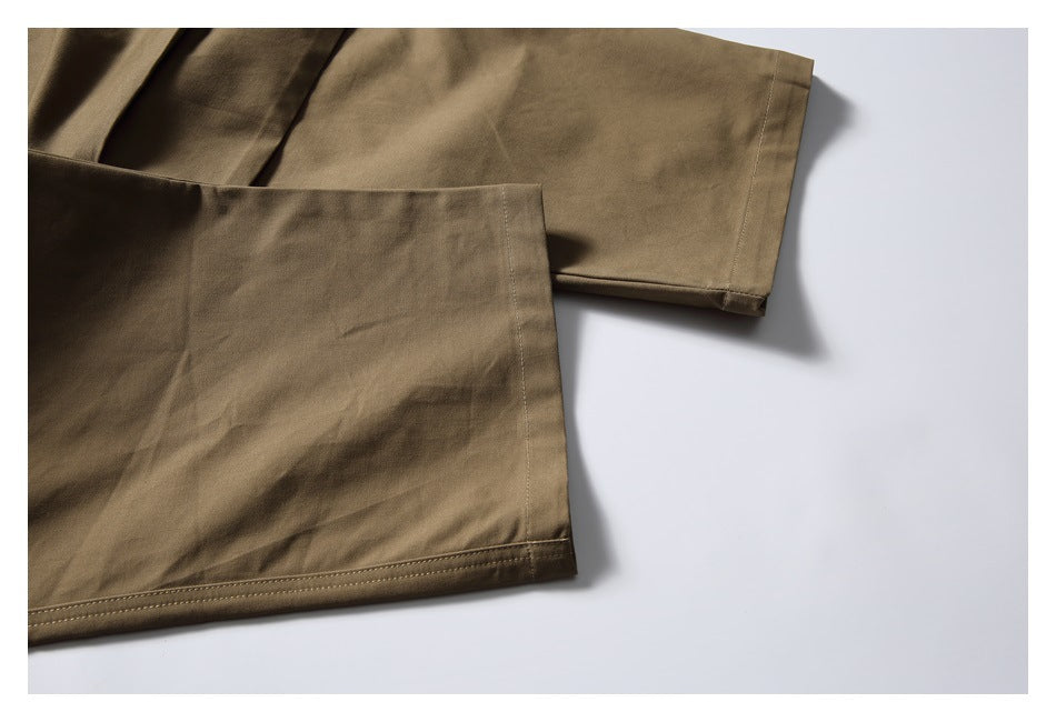 Close-up of overlapping khaki trouser legs showing stitched hems and seams.