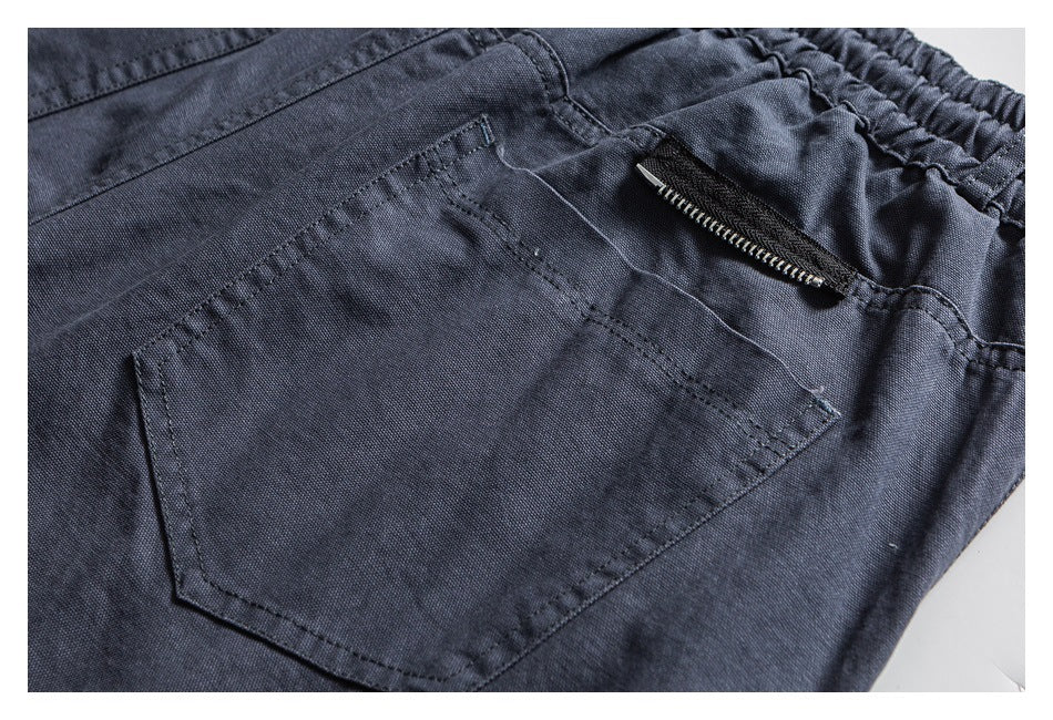 Close-up of a stitched pocket and zipper on dark charcoal shorts.