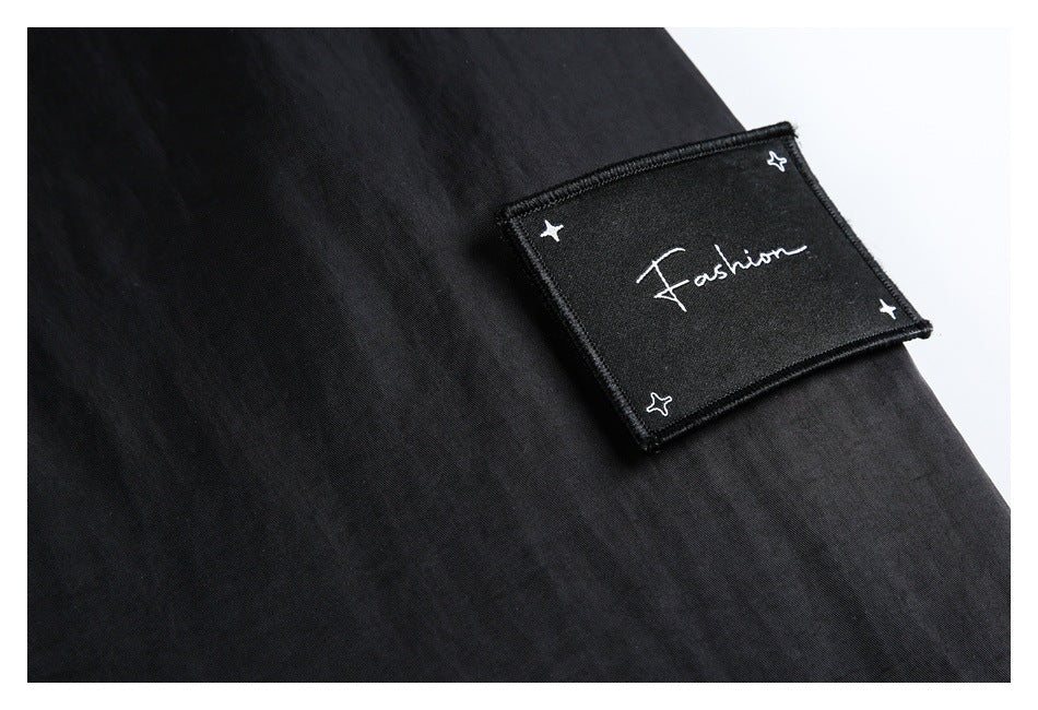 Close-up of a black garment patch embroidered with the word “Fashion” and small stars.