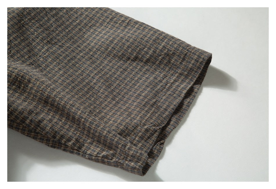Close-up of a finished edge on brown, blue, and tan checked garment fabric.