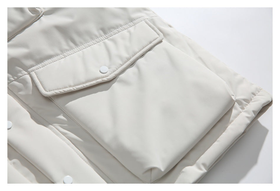 Close-up of an ivory jacket’s large flap pocket with a white snap and quilted edge.