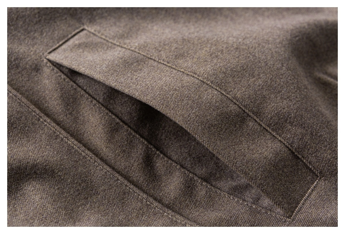 Close-up of a slit pocket on brown textured coat fabric.