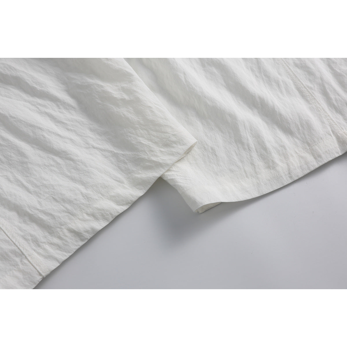 Close-up of the hem and softly wrinkled fabric on white wide-leg pants.