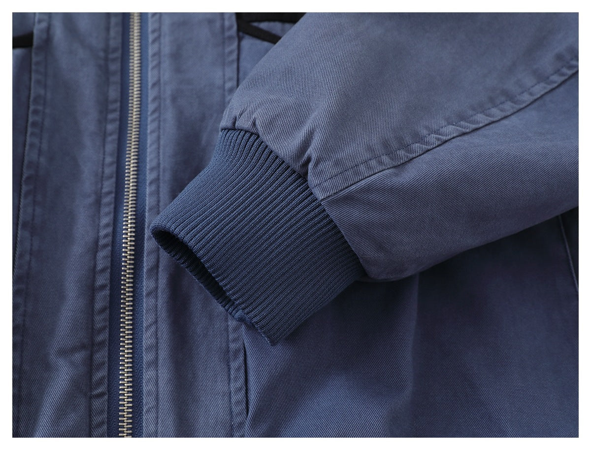 Blue-gray jacket sleeve with a dark ribbed cuff beside the front zipper.