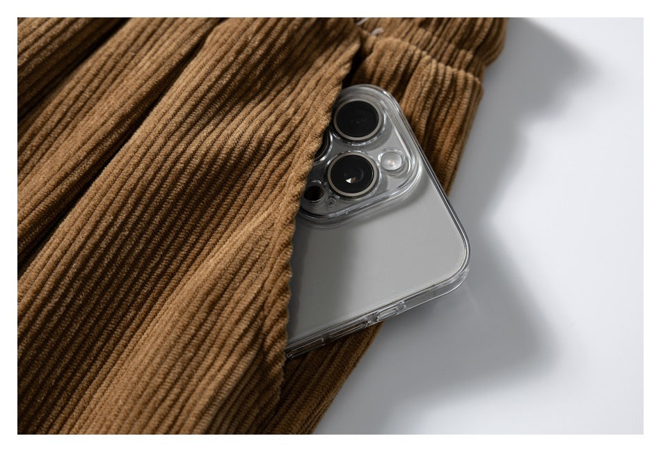 Close-up of brown ribbed corduroy pants draped over a silver smartphone on a white surface.