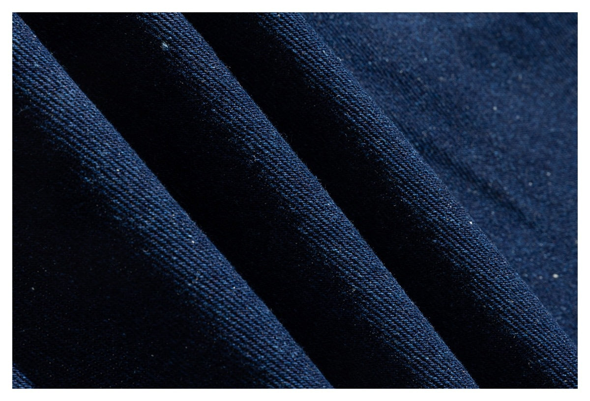 Macro view of dark indigo denim fabric folded to show its woven texture.