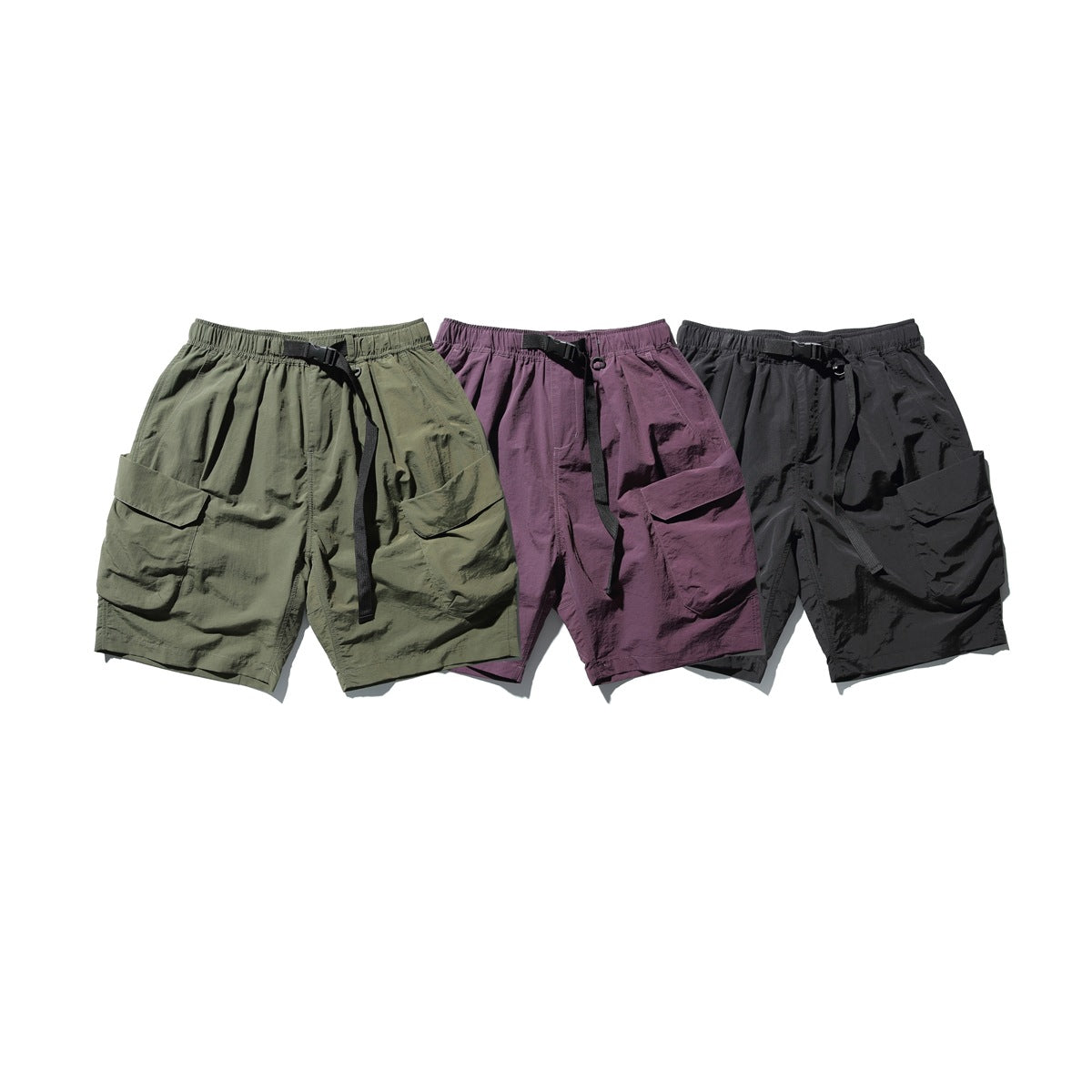Three pairs of cargo shorts with elastic waists and black belts in olive, muted purple, and charcoal.