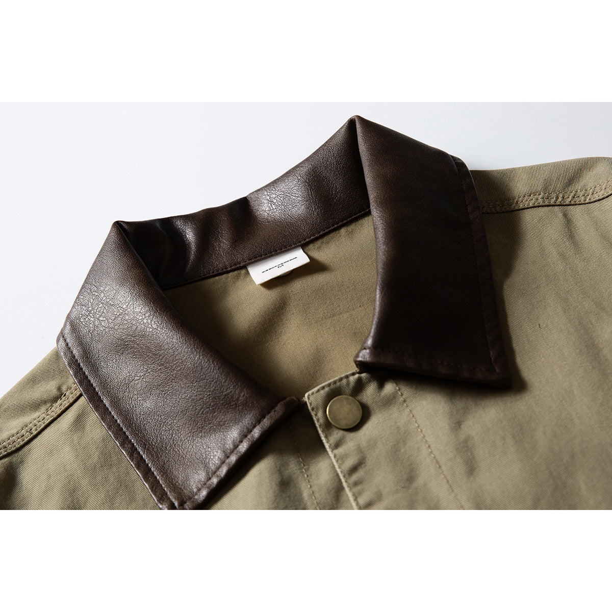 Close-up of an olive-khaki jacket with a dark brown collar and brass-tone snap.