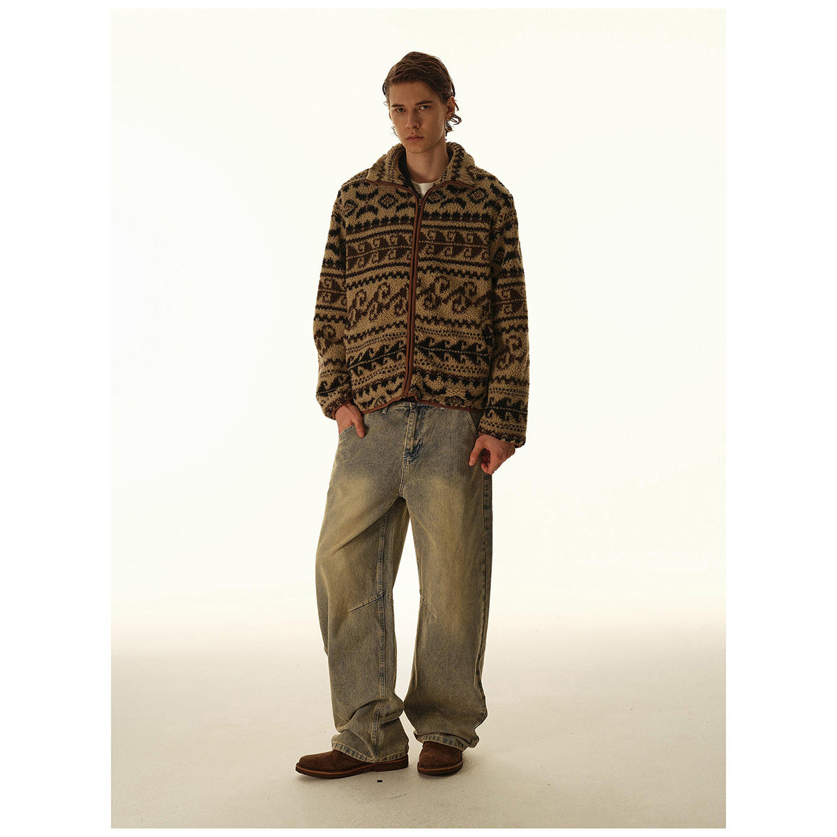 Man models a brown and black patterned zip-front fleece jacket with a collar, paired with loose faded jeans.