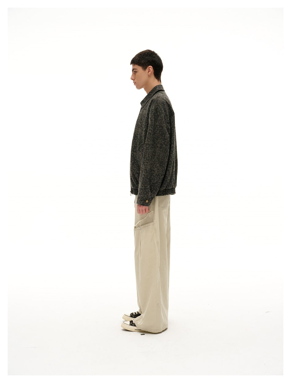 Side profile of a model wearing a dark olive leopard-print jacket and loose beige trousers.