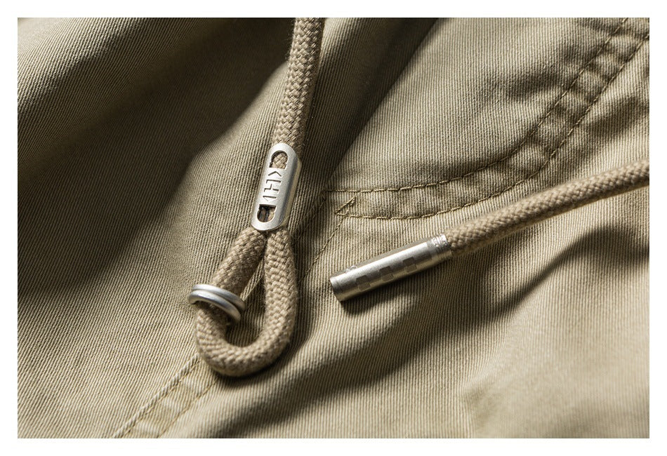 Close-up of braided khaki drawcords with metal tips and a stopper against the shorts fabric.