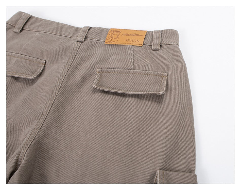 Close-up of the back of taupe trousers with flap pockets, belt loops and a tan waistband patch.