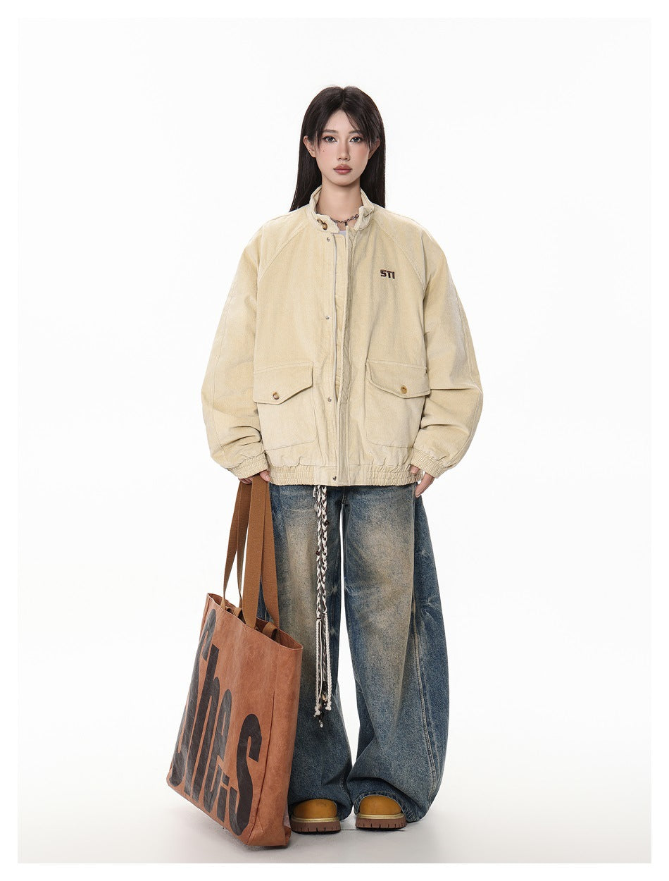 Model wearing khaki corduroy stand-collar jacket with wide-leg jeans and a large orange tote bag