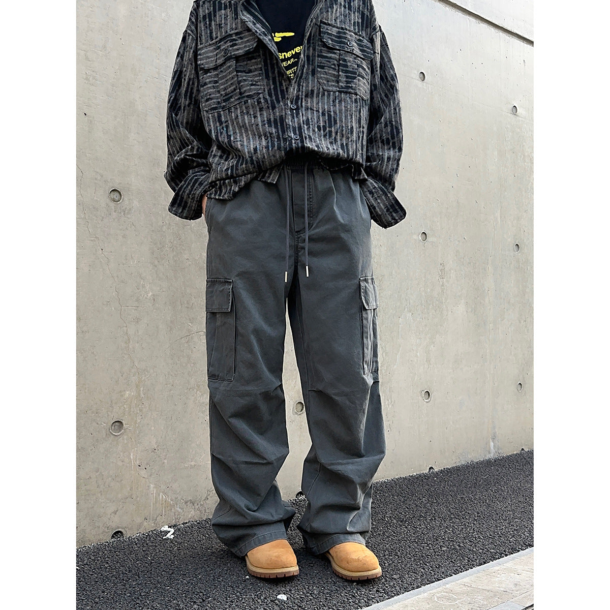 Model wearing dark charcoal cargo pants with an elastic drawstring waist and flap pockets on both legs.