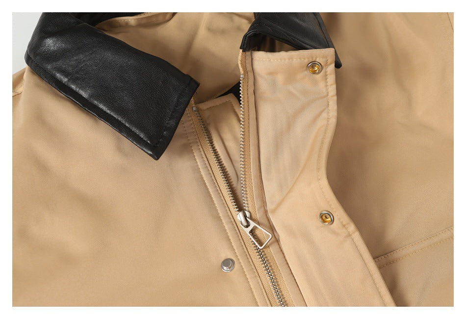 Close-up of a tan jacket with a black collar, metal zipper, and snap-fastened front placket.