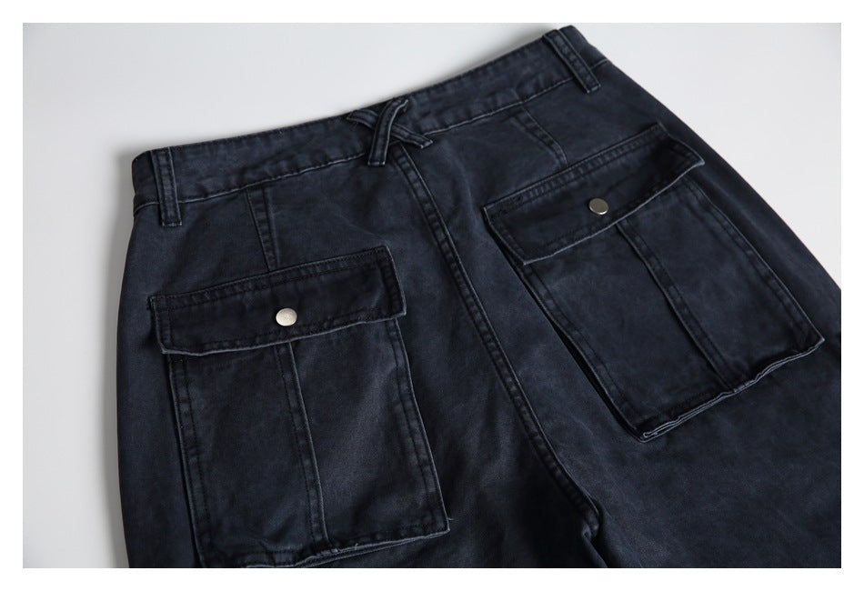 Close-up of dark charcoal trousers with a drawstring waist and large flap cargo pockets.