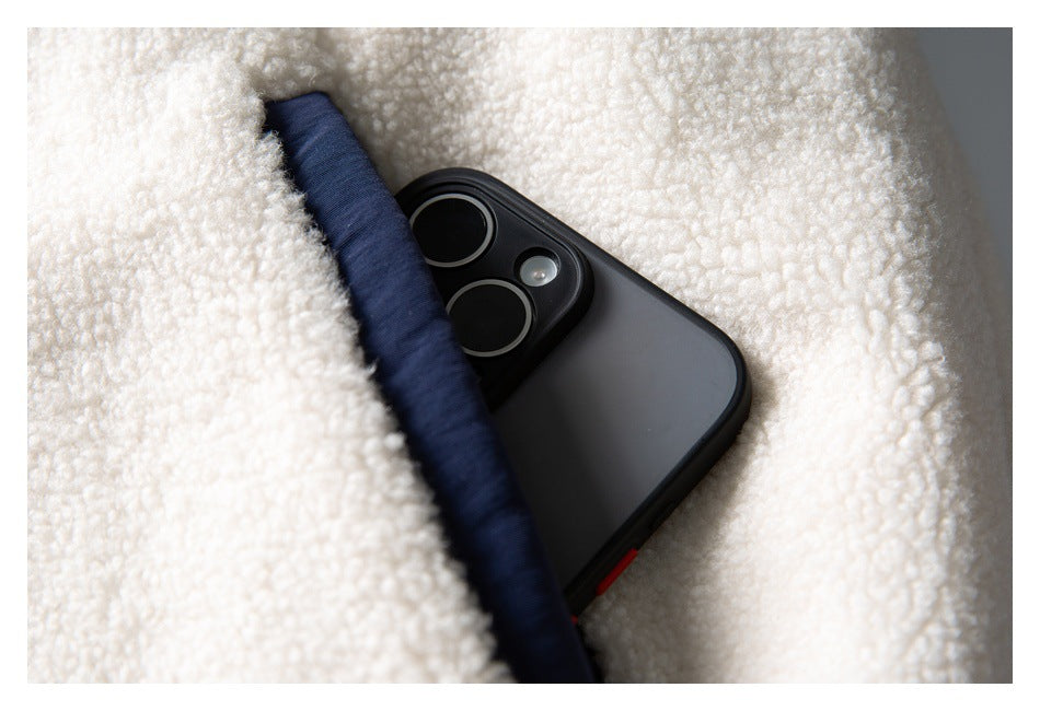 Close-up of a dark phone tucked into a pocket or opening in a cream and navy fuzzy garment.