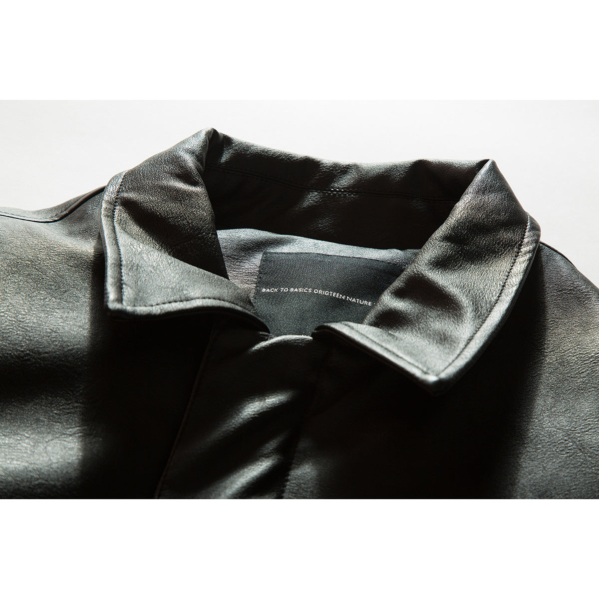 Close-up of a black jacket's wide folded collar and inner label with small English text.
